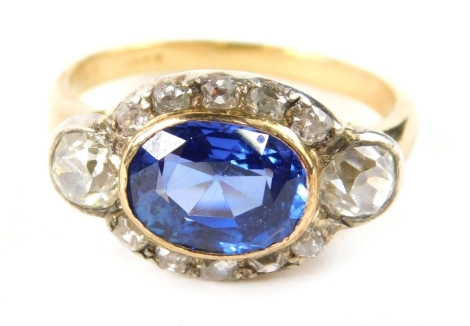 A Burmese sapphire and diamond oval dress ring, the oval cut sapphire in a gold rub over setting 9.2mm x 7mm x 4mm, flanked by old cut diamonds, two large approx. 0.33ct, with a halo of ten tiny diamonds, ring size Q½, 5.1g all in.