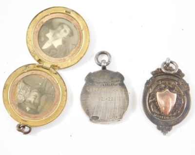 A silver and yellow metal fob, marked Marsh Village League Division One, a photograph frame pendant, 3cm diameter, and a silver and silver gilt fob medallion, The Bellamy Cup 1921-2. (3) - 2