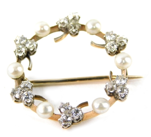 A seed pearl and diamond circular brooch, set with three leaf clovers, each with tiny diamonds in claw setting, with cultured pearl breaks, on a single pin back, yellow metal, unmarked, 2.5cm diameter, 4.4g all in.