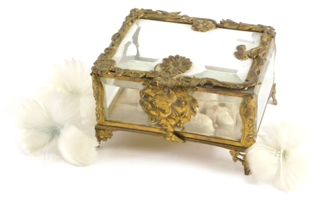 An early 20thC glass and gilt metal casket, with shaped panels, hinged lid on paw feet, with elaborate floral lock, unmarked, 14cm wide.