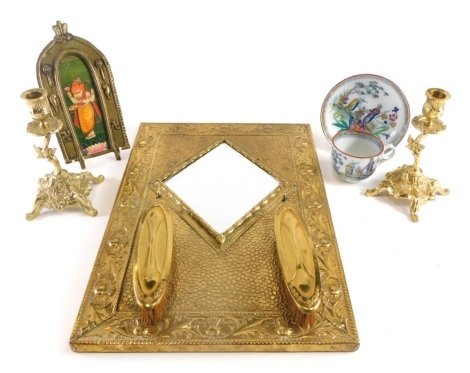 Various metalware, a pair of brass rococo style candlesticks, 20cm high, a brass hanging mirror with brushes, a frame set with an Indian god, and a pottery teacup and saucer