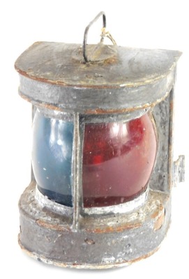 An early 20thC ships lamp, with red glass centre and swing carrying handle, the main body 26cm high.