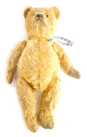 A mid 20thC blonde plush jointed Teddy Bear, with glass eyes embroidered nose and mouth, with a ribbon to the neck, 53cm high.