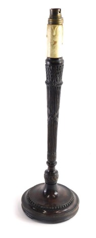 An early 20thC carved mahogany neoclassical candlestick, with metal fitting on tapering stem and circular foot, with a bead decoration, 48cm high.