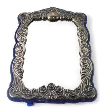 A silver plated photograph frame, decorated with scrolls with a vacant cartouche and plain blue baize easel back, 27cm x 19cm.