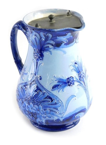 An early 20thC Moorcroft Florian ware jug, with metal lid, shaped handle on circular foot, printed marks beneath, lacking Moorcroft signature, 19cm high.