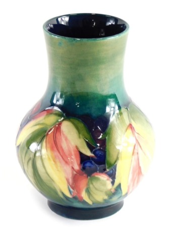 A mid 20thC Moorcroft pottery Leaf and Berry pattern vase, on green ground, with globular body on circular foot, impressed marks beneath, 18cm high.