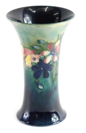 A mid 20thC Moorcroft pottery Spring Flowers and Orchids pattern vase, of inverted trumpet form, on circular foot, impressed and signature marks beneath, 21cm high.