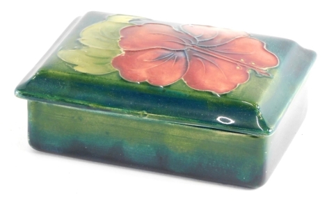 A mid 20thC Moorcroft Hibiscus pattern box and cover, of rectangular form on green ground, impressed marks beneath, 12cm wide.