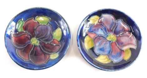 Two 20thC Moorcroft pottery Anemone pattern saucers, on blue ground, Queen Mary labels beneath, 7cm diameter.