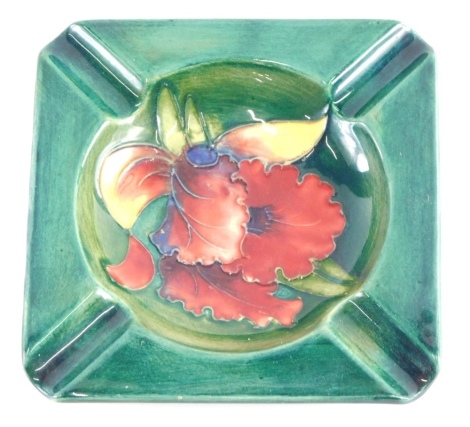 A mid 20thC Moorcroft pottery Orchid pattern ashtray, on green ground, impressed mark with label beneath, 12cm wide.