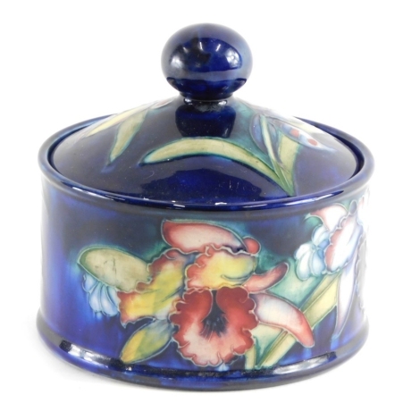 A Moorcroft pottery box and cover, of circular form with domed lid, on blue ground, impressed marks beneath with label, 13cm high.