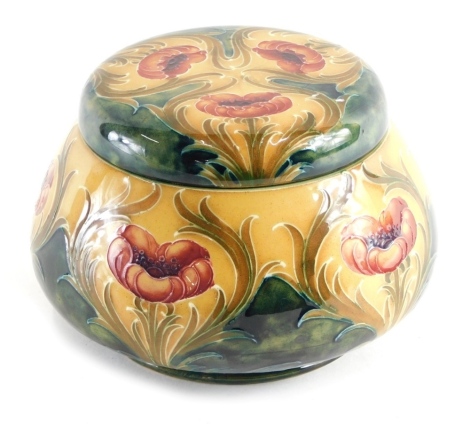 An early 20thC Moorcroft Macintyre Poppy on ochre ground pattern tobacco jar and cover, with screw top on yellow and green ground, printed marks, and WM signature mark beneath, 13cm high.