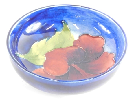 A 20thC Moorcroft Hibiscus pattern bowl, of circular form on a circular foot, on blue ground, impressed marks beneath, 11cm diameter.