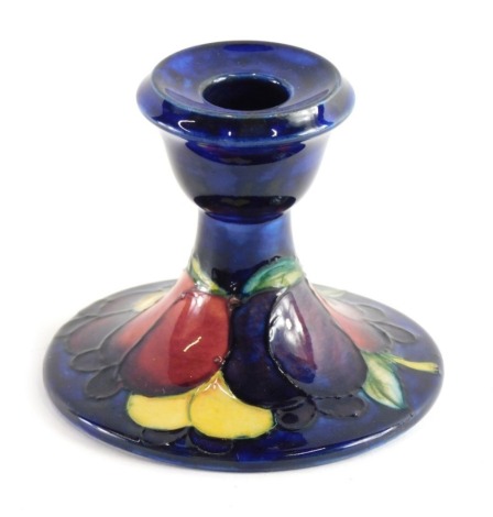 A Moorcroft Wisteria pattern candlestick, on blue ground, impressed and signature marks beneath, 9cm high.