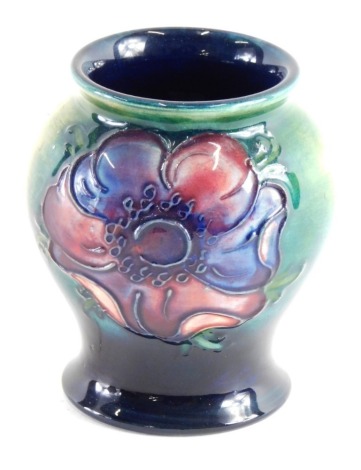 A Moorcroft pottery vase, on green ground, on circular foot, impressed marks beneath, 8cm high.