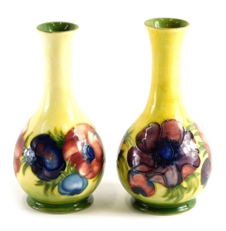 Two similar Moorcroft pottery vases, on yellow ground, on circular feet, impressed marks beneath, 18cm high. (2)