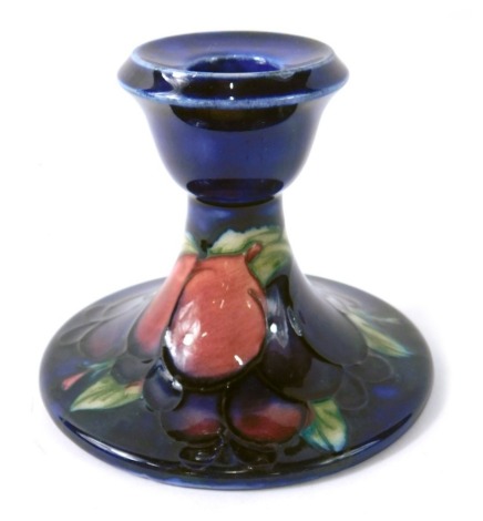 A Moorcroft pottery Wisteria pattern squat candlestick, on blue ground, impressed marks beneath, 9cm high.